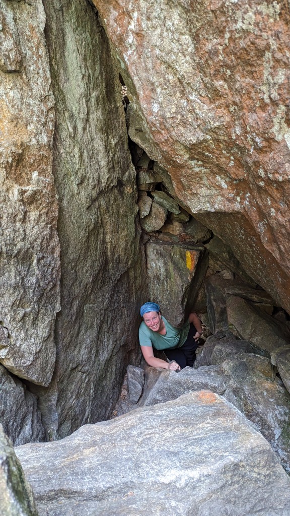 A woman in an impossibly tight passage through gigantic boulders